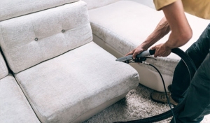 Man using a vacuum cleaner to clean a couch. Helpful cleaning tips