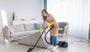 A woman efficiently cleans a room with a vacuum cleaner, following helpful cleaning tips.