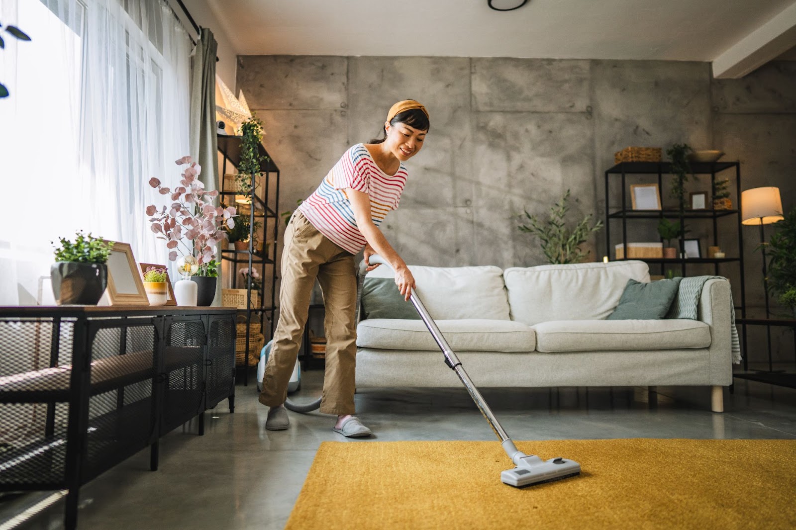 A woman vacuums a room, emphasizing seasonal cleaning and home disinfecting services for a healthier living space.